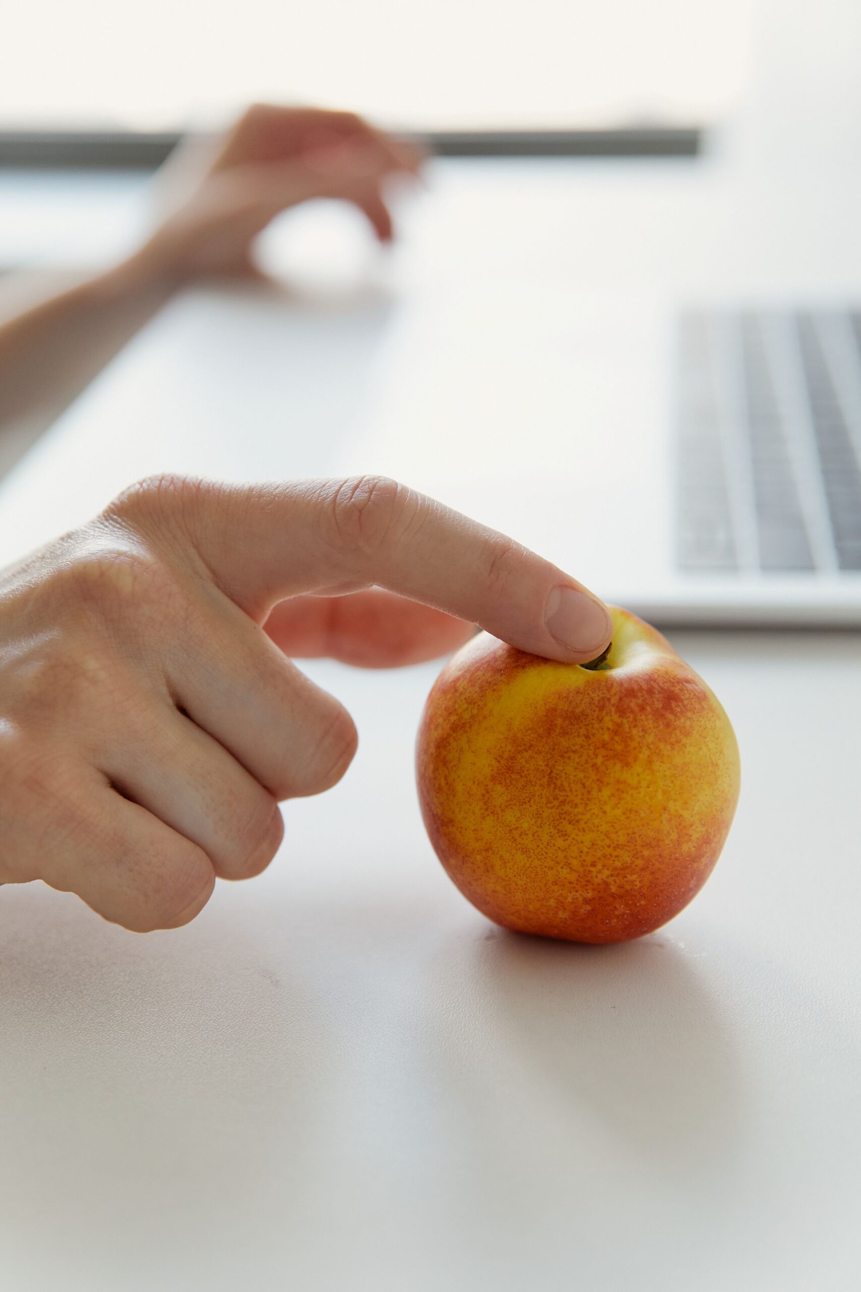 Büro mit PC und einer Hand mit Apfel 